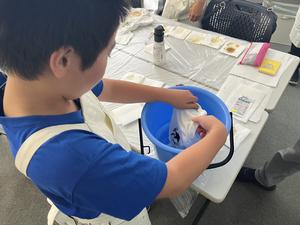 子どもが洋服をバケツの中ですすいでいる様子