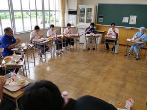 机を円にしてみんなでなまずドッグを食べる様子
