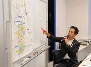 ホワイトボードに用いて説明する市長
