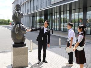 一日市長に庁舎前の森と鯰の石像の説明をする市長