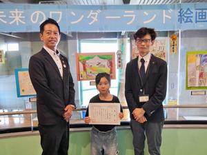 絵画展示会場で優秀賞の関小学校2年生の麦屋寧さんと市長、館長との記念撮影
