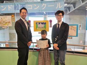 絵画展示会場で館長賞の美南小学校3年生の馬場音羽さんと市長、館長との記念撮影