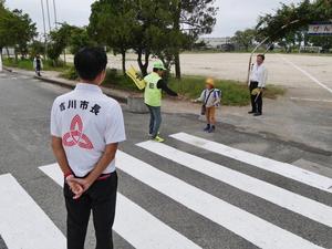 登校する児童が前自治会長とじゃんけんする様子を見守る市長