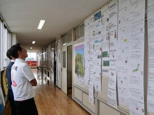 廊下に掲示されている生徒のプレゼン資料を見る市長