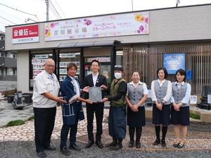 なまりんイラストーンを手に社員の皆さんと記念撮影する市長