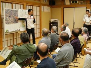 航空写真を指差して説明する市長
