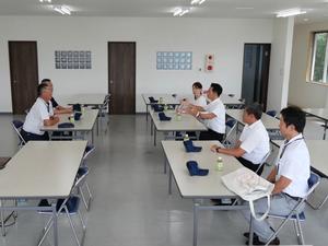 事務所内で社長の説明を聞く市長と市職員