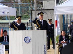 行進する消防団員に壇上より敬礼する市長