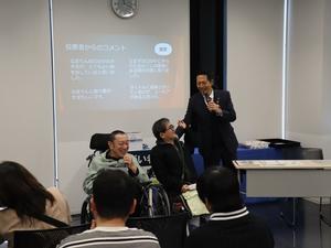 表彰式で受賞の感想を述べる受賞者と笑顔で肩をたたく市長