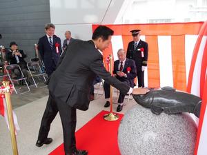 モニュメントのなまずを撫でる市長