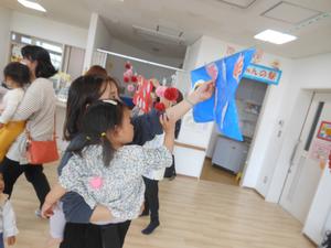 青いこいのぼりに手形を貼る親子の写真