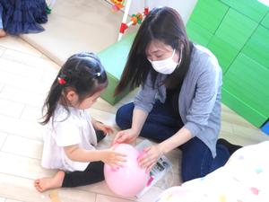 風船にシールを貼っている女の子とママ。