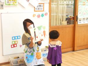 紙芝居の読み聞かせを間近で見ている女の子の様子