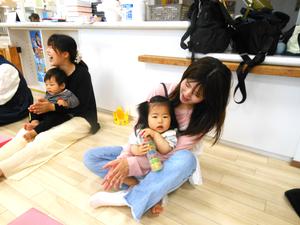 おもちゃを抱えてママのおひざに座っている誕生児の女の子