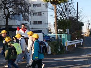 児童に笑顔で手を振って挨拶をする市長