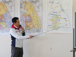 図を指示棒で指して説明する市長