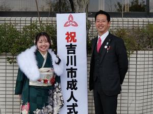 屋外の成人式立て看板前で市長と新成人との記念撮影