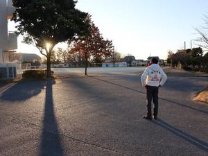 朝日を受けて校門に立つ市長