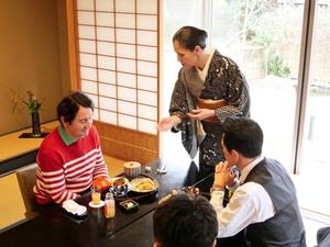 福寿家の女将よりなまず料理の説明を受けるピーター氏