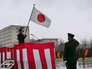 壇上の国旗に敬礼する自衛官