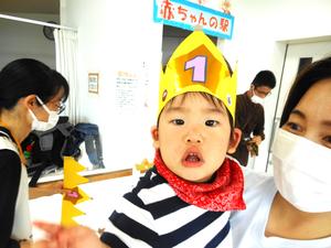 ママに抱かれる、冠をかぶっているお誕生児の男の子の写真