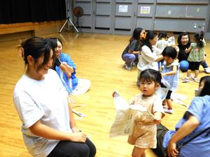 新聞紙をちぎる女の子とその様子を見ているママの写真
