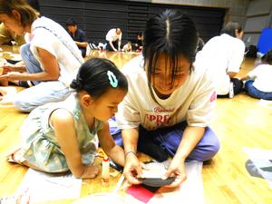 うちわ工作で、パパのの顔を作っている親子の様子
