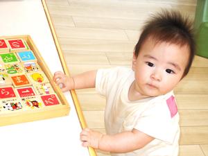 つかまり立ちしてカメラを見る9ヶ月の男の子の写真