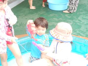 プールの中で、じょうろや水鉄砲で水遊びを楽しむ3姉弟の様子