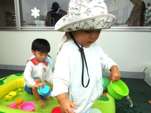 プールのお水をカップでかき出す男の子たちの様子