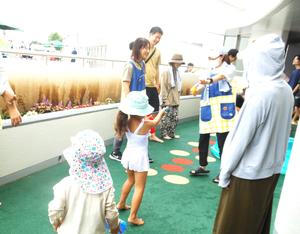 女の子と保育士が水鉄砲で水を飛ばし合う様子
