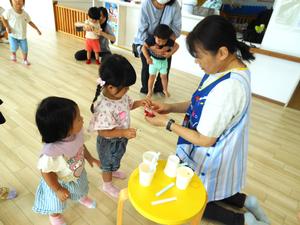 保育所の先生から、工作のパーツをもらっている姉妹の様子