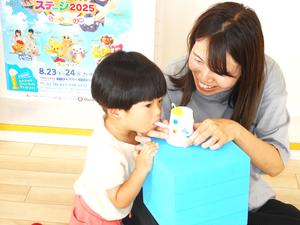 ストローに息を吹き込む男の子と笑顔のママの写真