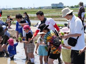 子供と一緒に田植えをする市長
