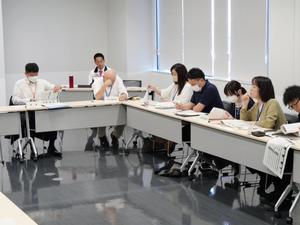 会議で意見する委員と傍聴する市長