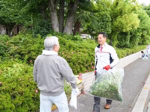 収集した草を集めた袋を持って文化連盟高田会長と話をする市長
