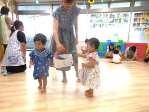 完成した作品（ぶどうを入れたバッグ）を持ってお散歩する親子と女の子の様子