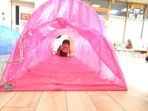 ピンク色のトンネルをハイハイでくぐっている女の子の様子