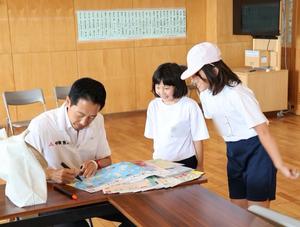 市長のサインをもらいに来た児童とサインする市長