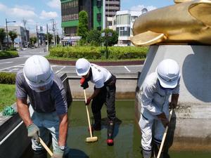 デッキブラシで池の底を磨く市長と職員