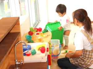 講座中の同室託児で、保育ボランティアさんとおままごとをしている男の子の様子