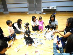 先生とみんなで、新聞をちぎって遊んでいる様子