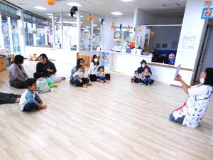 紙芝居を読む保育士と親子達の様子