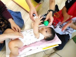 おもちゃであやしながら体重を測定している様子