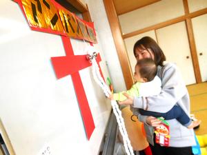 お参りごっこで、ママに抱っこされて鈴を鳴らす赤ちゃんの様子