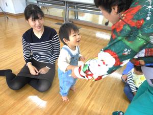 絵本を広げている講師の先生に近寄る男の子と見守るママの様子