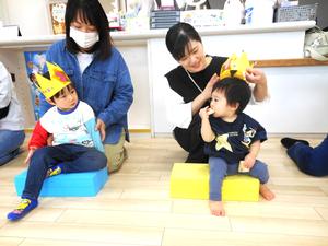 誕生児の男の子がカラーつ向きに座って見つめ合っている様子