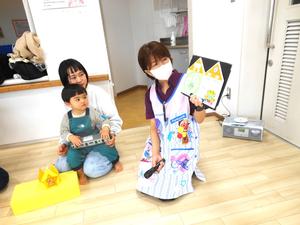 ママの膝に座っている誕生児の男の子と誕生日カードを紹介している保育士の様子