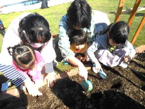 花壇の土をシャベルで掘っている2組の親子の様子