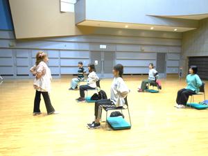 正しい姿勢で椅子に座る指導を受けている様子